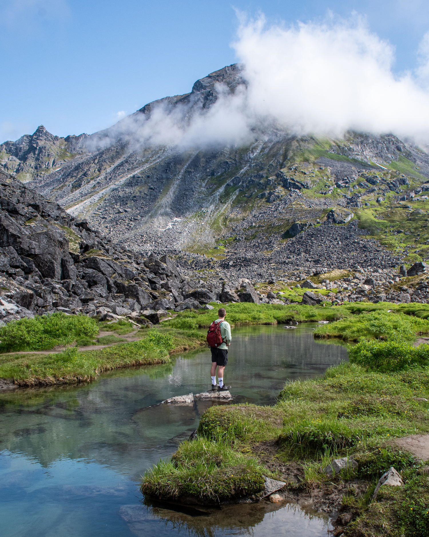 Boy standing on a rock in the river with mountains above