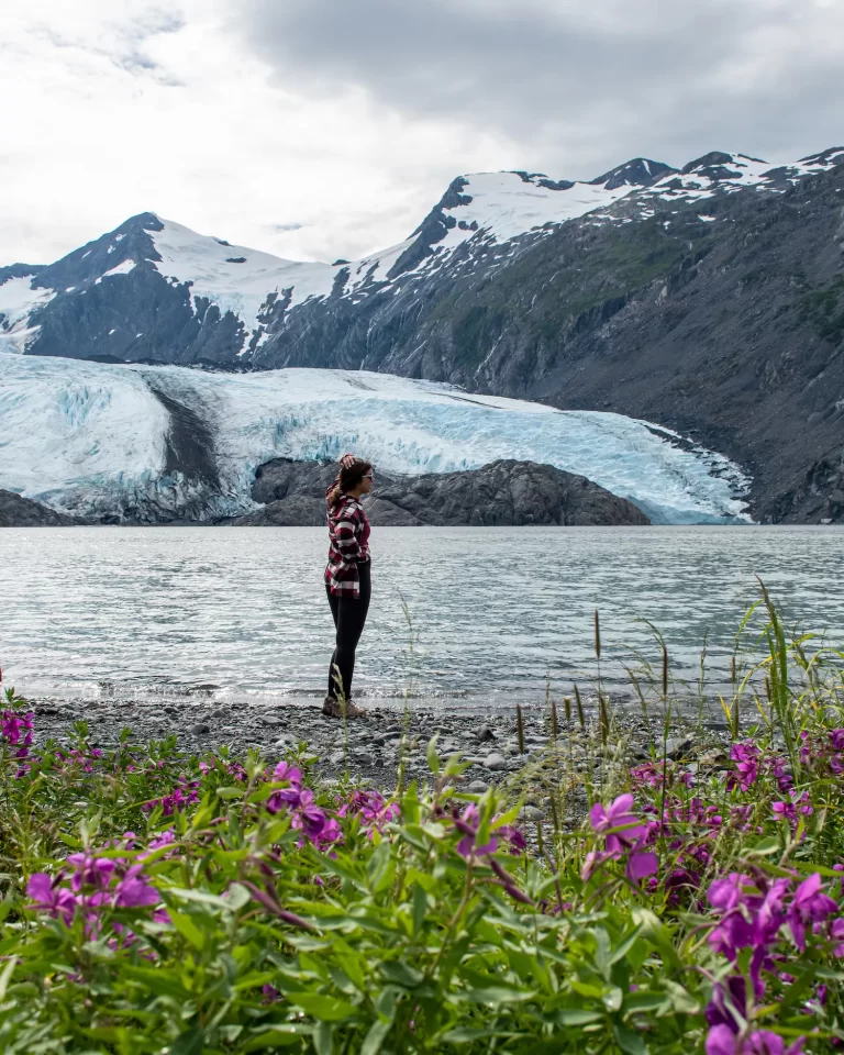girl standing with arm up in front of portage glacier