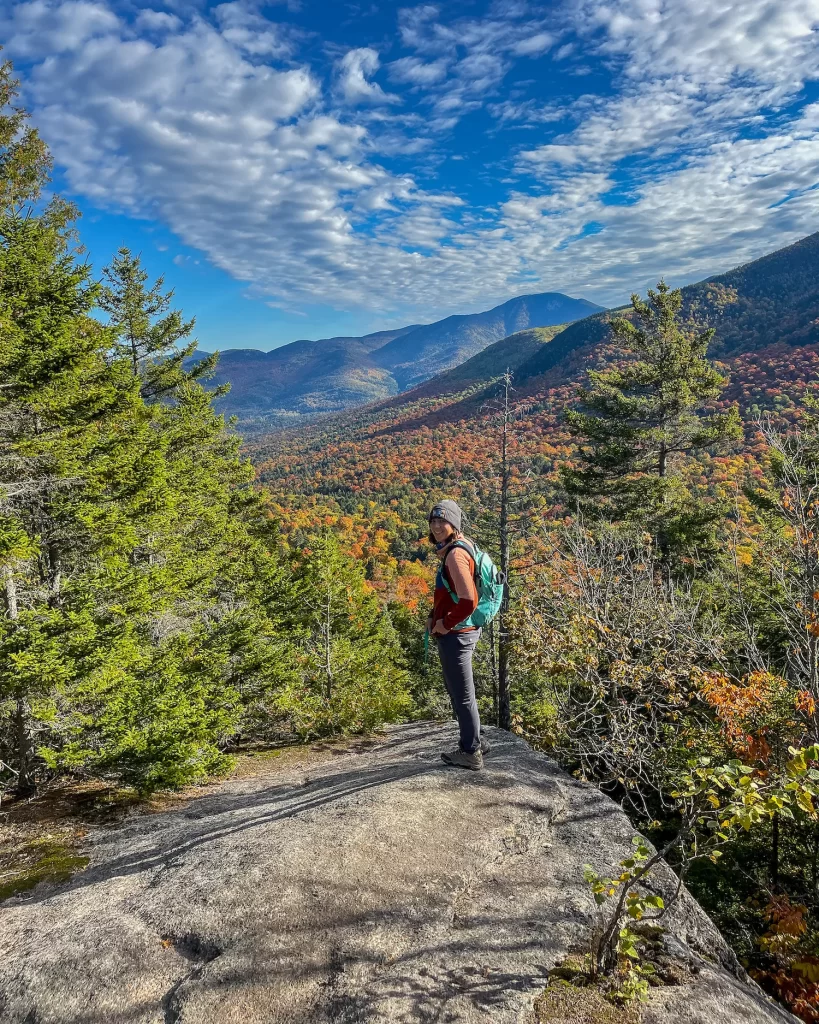 Girl standing on a mountain with trees all around her