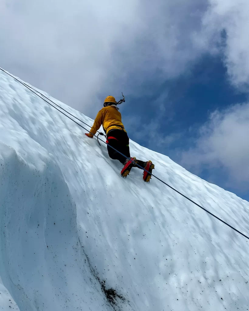 man ice climbing up the top of a glacier