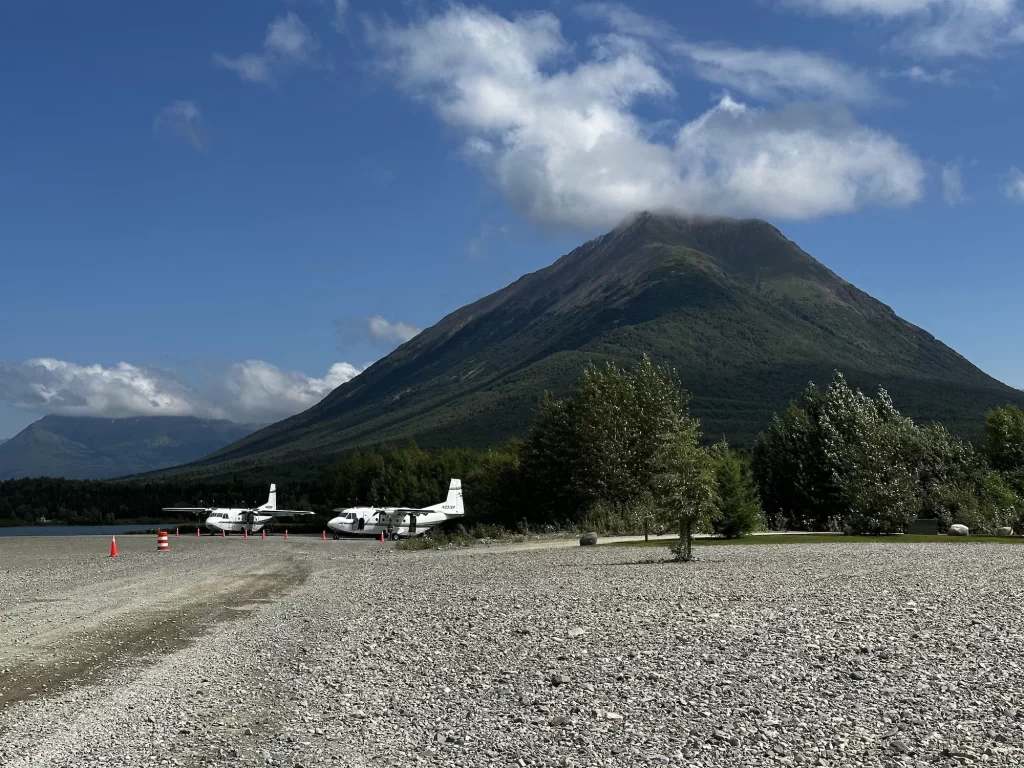 small charter planes on an airstrip below a mountain in lake clark