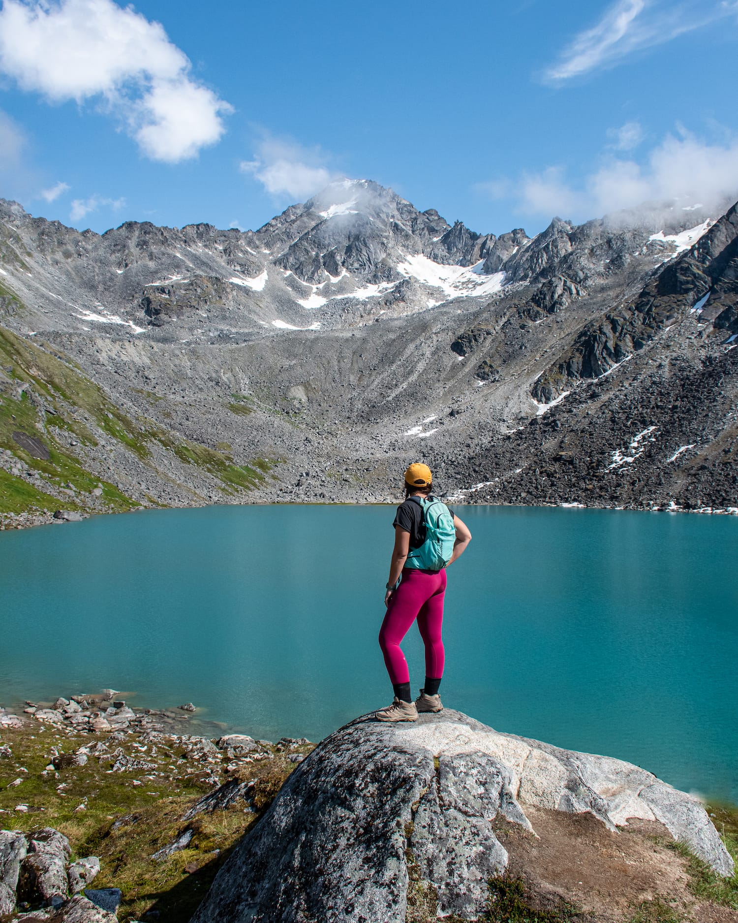 girl standing on a rock above reed lakes with the bright blue water behind her