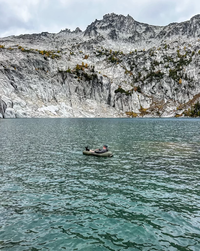 man floating in a raft in a lake in the enchantments