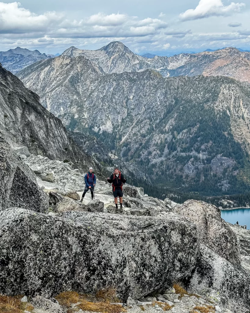 two guys standing with mountains behind