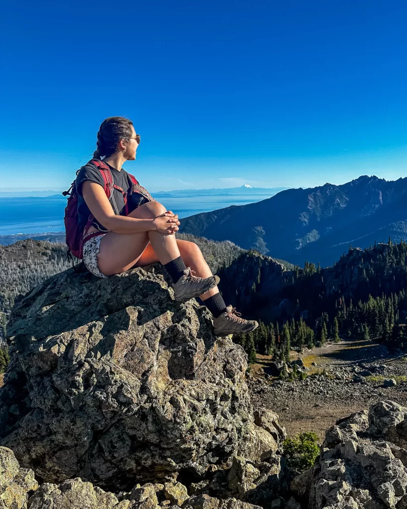 Woman looking out on a rock overlooking mountainous landscape