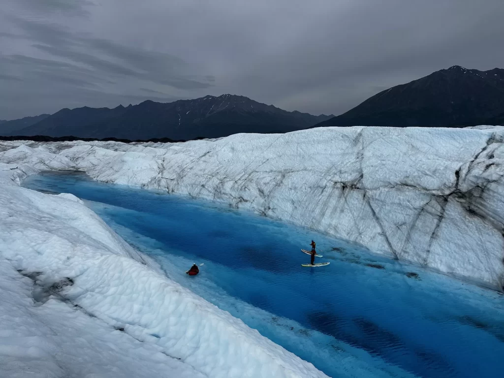 two people on paddleboards in a glacier pool