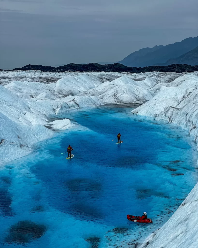 two people on paddleboards in a glacier pool