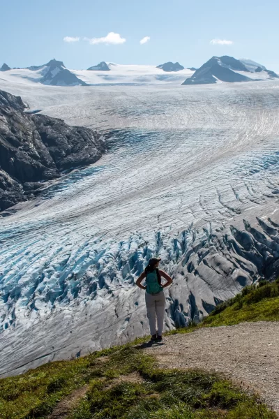 Woman standing and looking out with Exit Glacier and icefield behind her