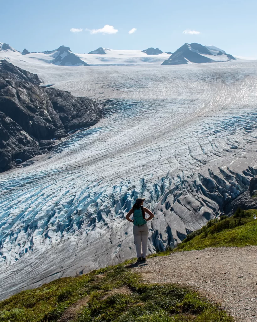 Woman standing and looking out with Exit Glacier and icefield behind her