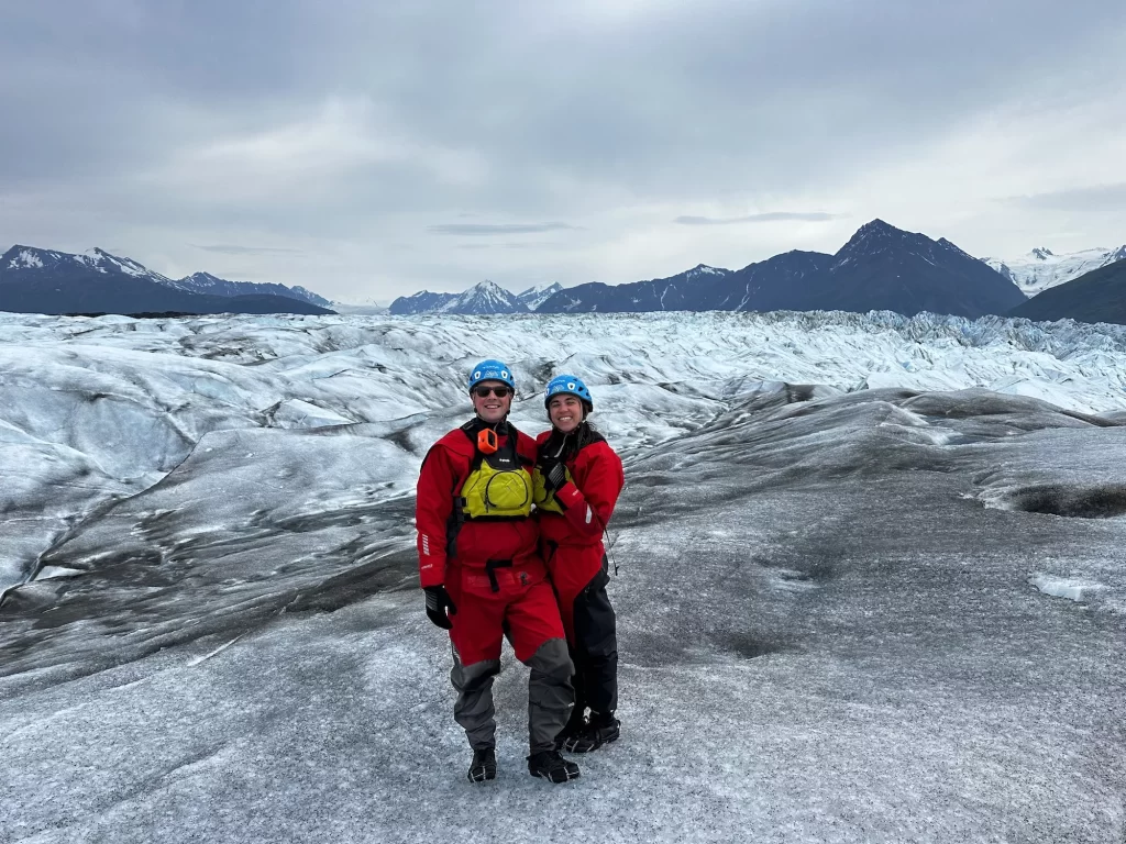 Two people on a glacier in dry suits