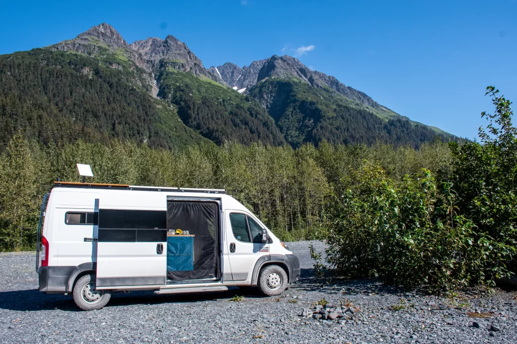 Van parked in front of a moutnain with doors open