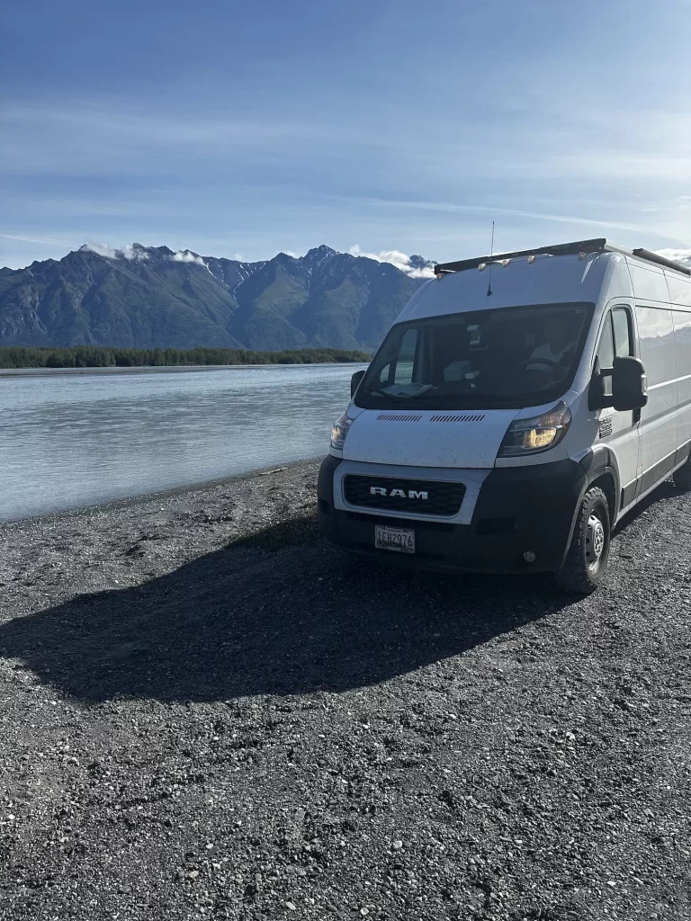 van at a campsite on the knik river with mountains behind 