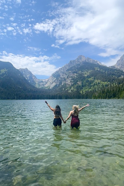 two girls at Taggart Lakes halfway in water with arms up