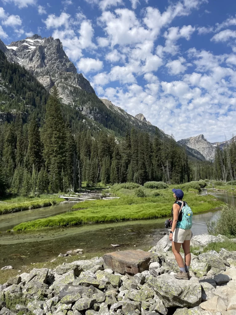 girl standing on trail with mountains behind her
