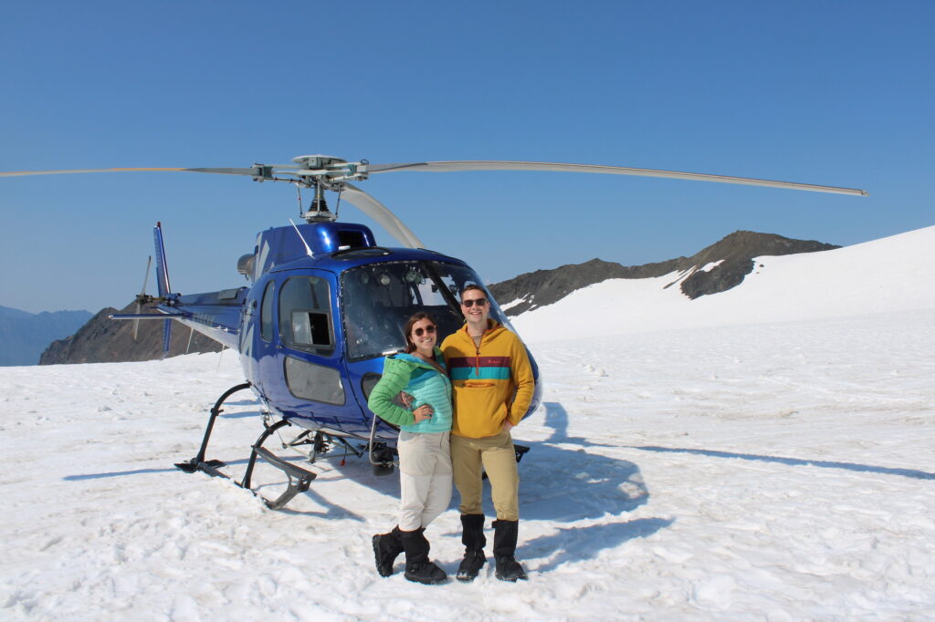 Two people standing in front of a helicopter