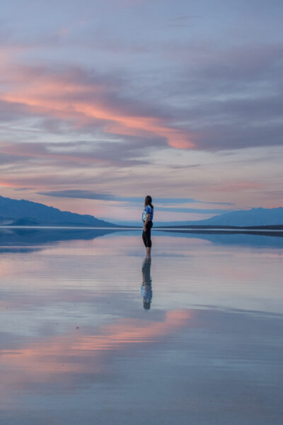 woman standing in lake manly with reflective sunset at death valley