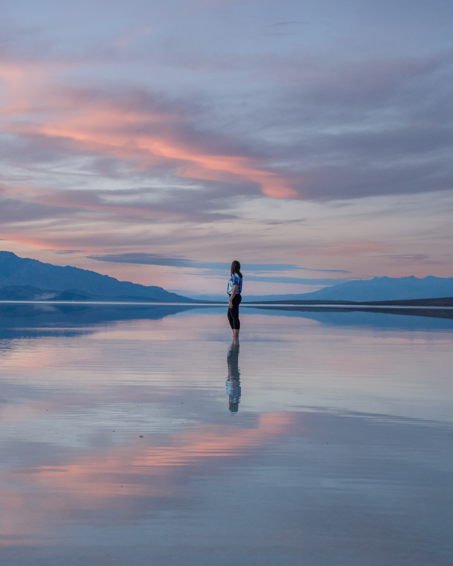 woman standing in lake manly with reflective sunset at death valley