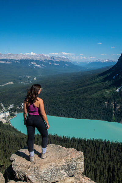 Girl standing at the top of the Little Beehive Hike over Lake Louise below