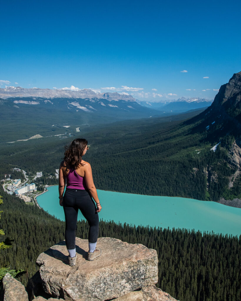 Girl standing at the top of the Little Beehive Hike over Lake Louise below