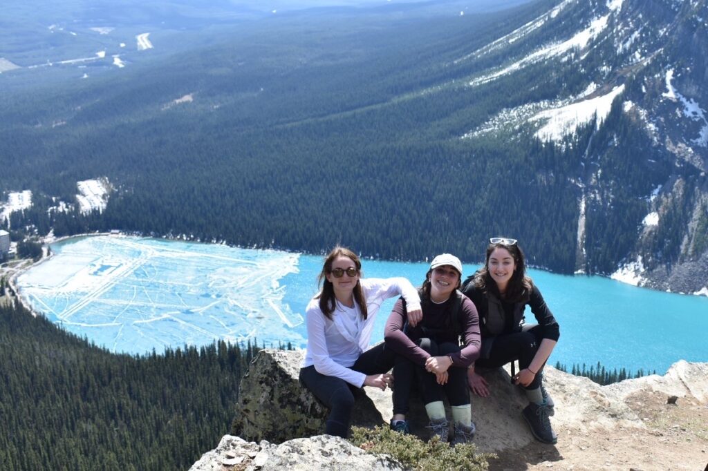 three girls sitting at the top of little beehive in lake louise