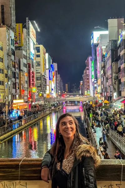 girl looking up at buildings in neon streets of osaka