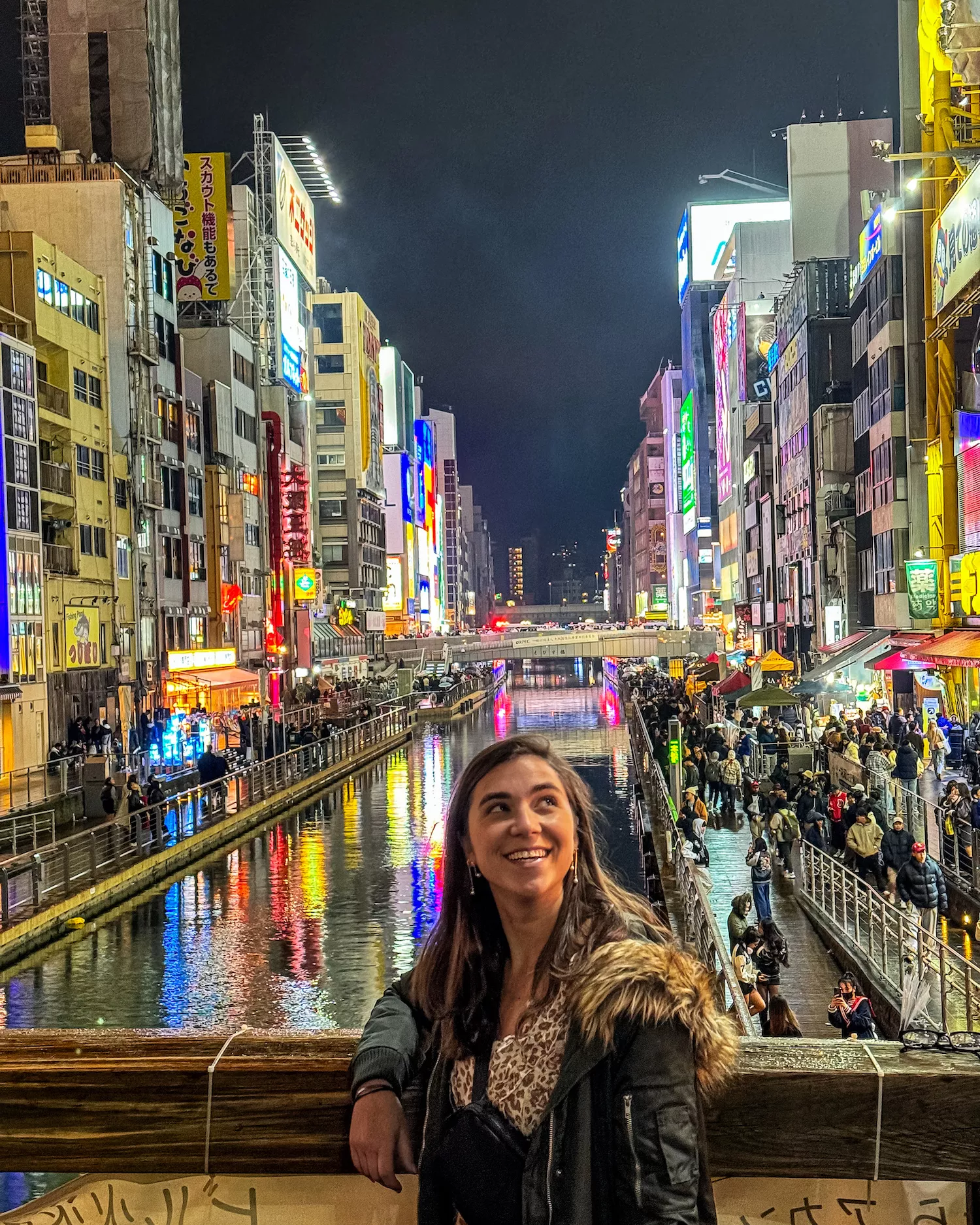 girl looking up at buildings in neon streets of osaka