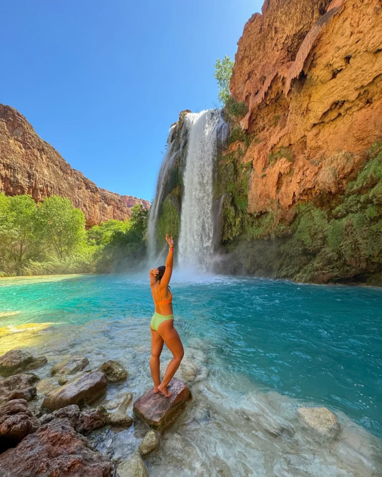 girl standing in front of Havasu Falls with her arm up