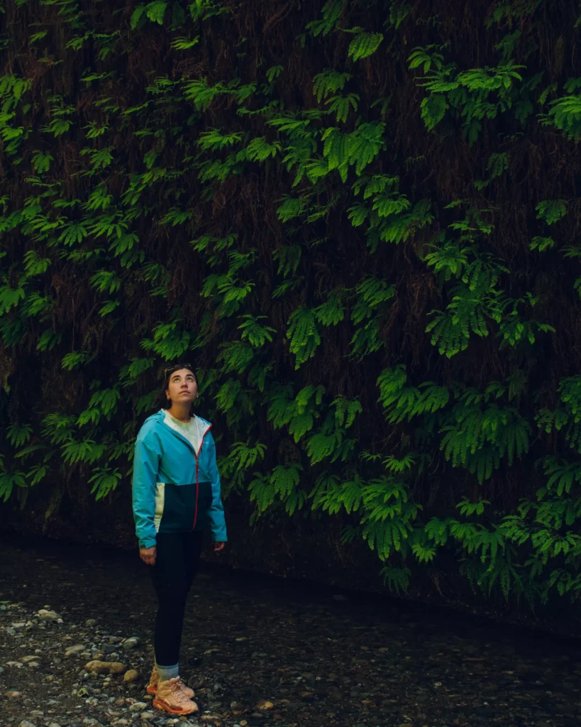 girl looking up with fern wall behind her