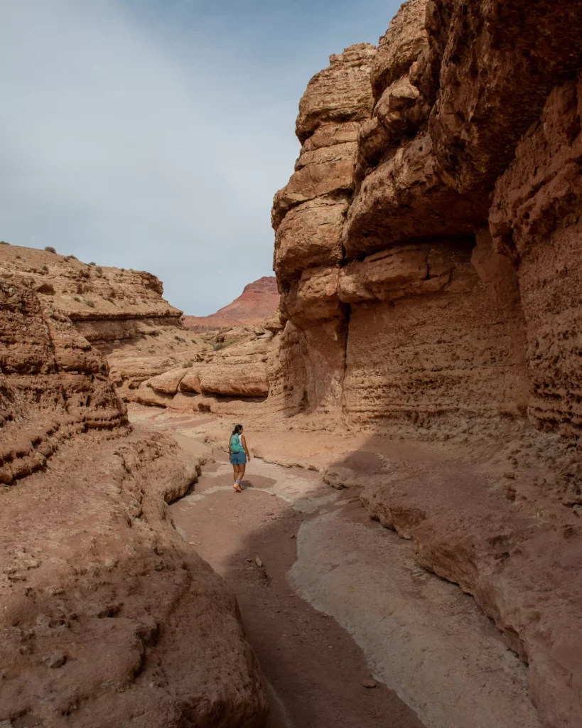 girl walking through slot canyon with backpack on
