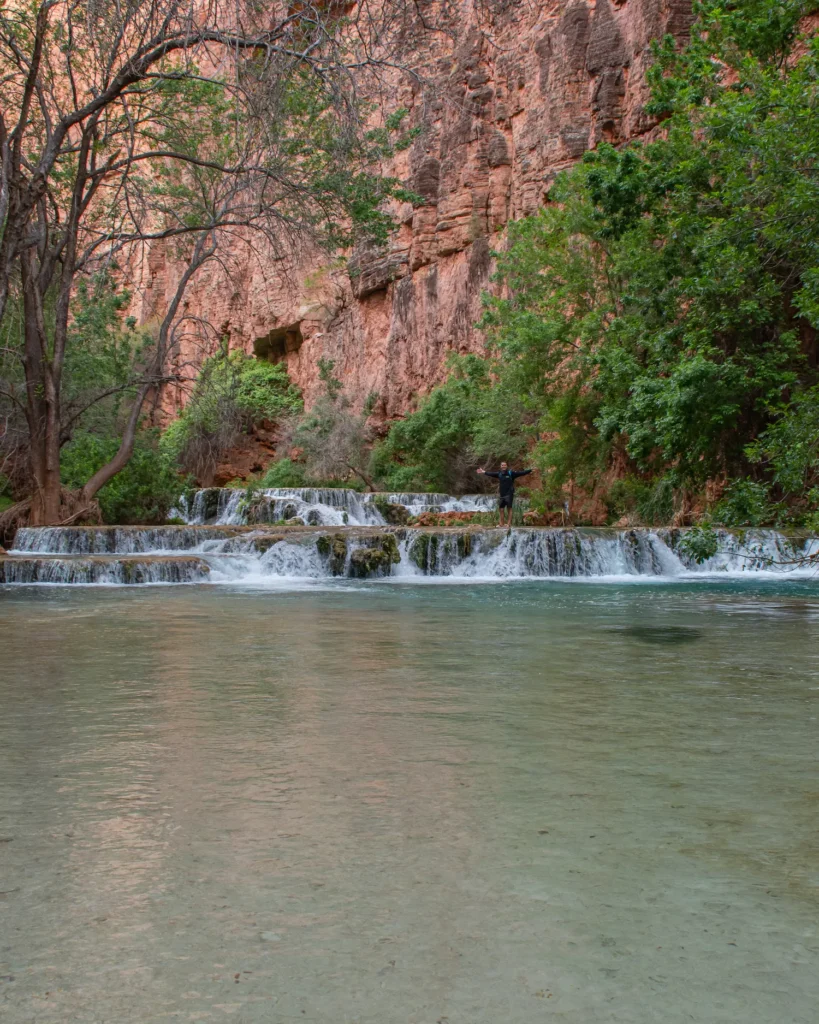 guy standing on waterfalls as they cascade down