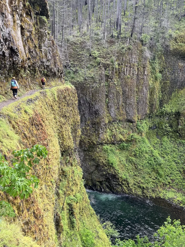 narrow ledge to twister falls iwth two people walking on it