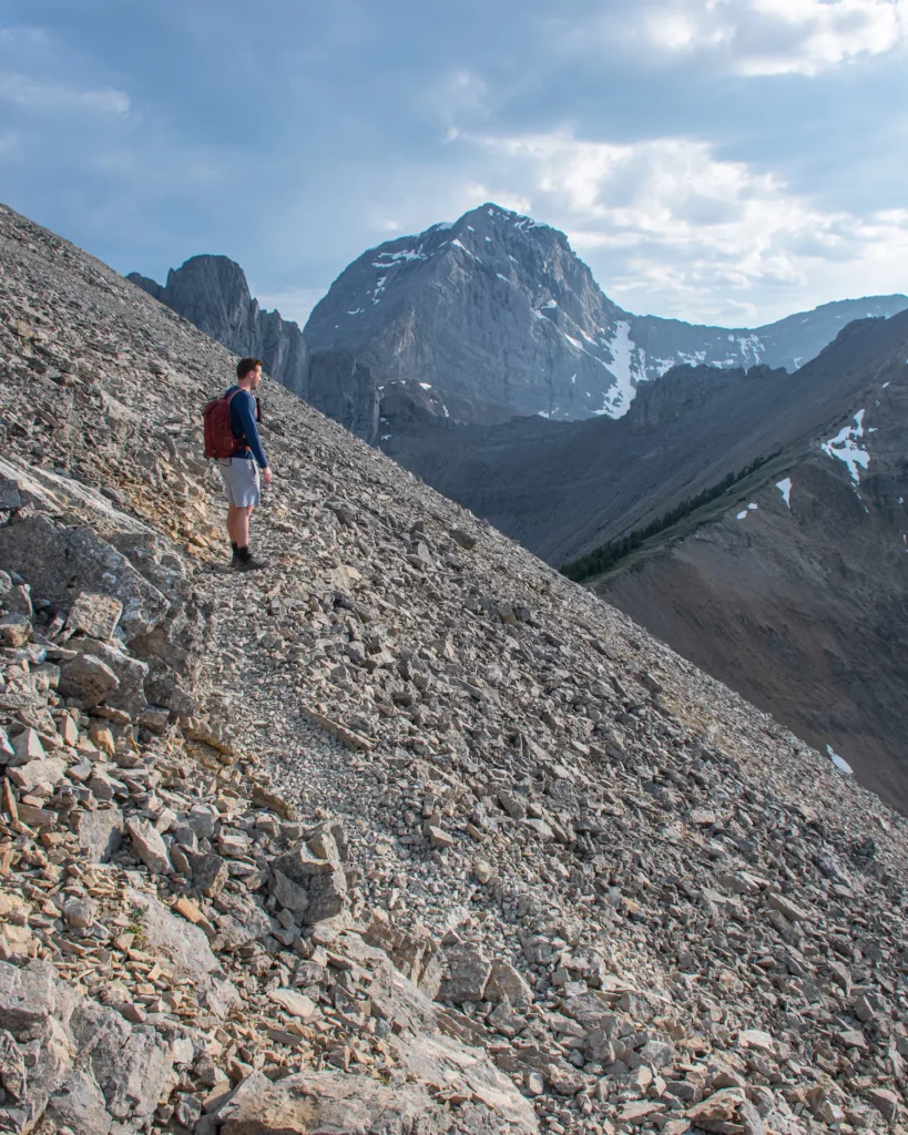 Guy standing on tent ridge looking over mountains
