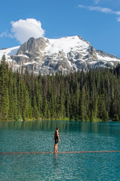 girl looking up at mtn as she is standing on a log in upper joffre lake