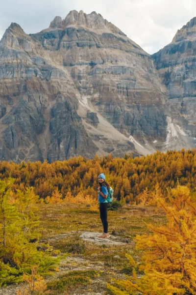 woman smiling while surrounded by larches with mountain above her on larch valley hike in banff