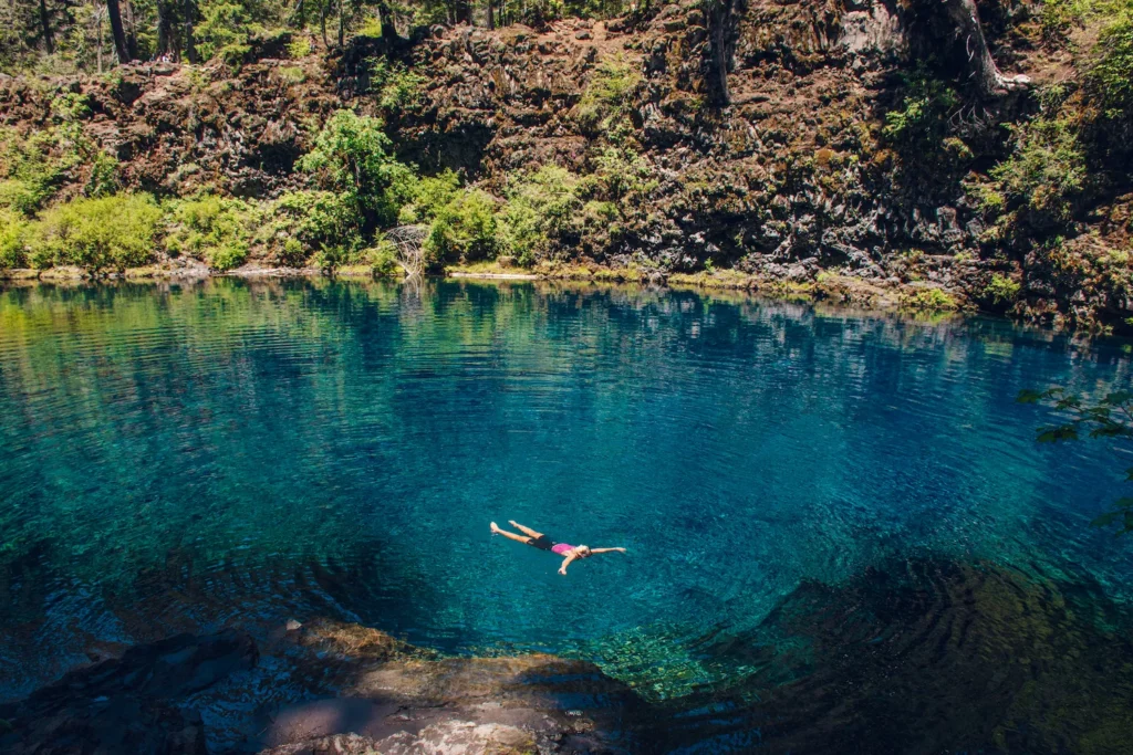 Woman floating in vibrant blue water of tamolitch falls blue pool