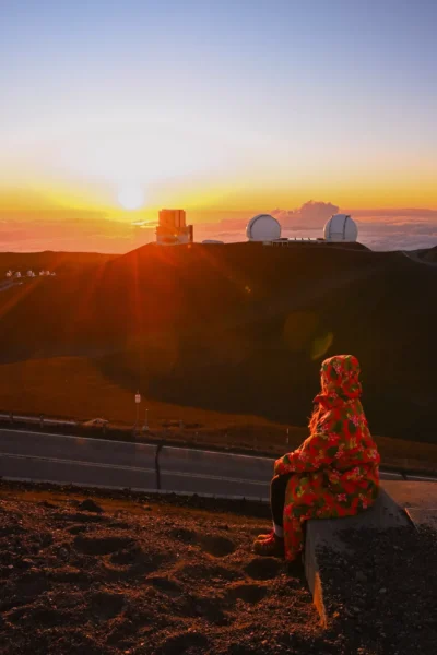 woman sitting on mauna kea looking over the sunset