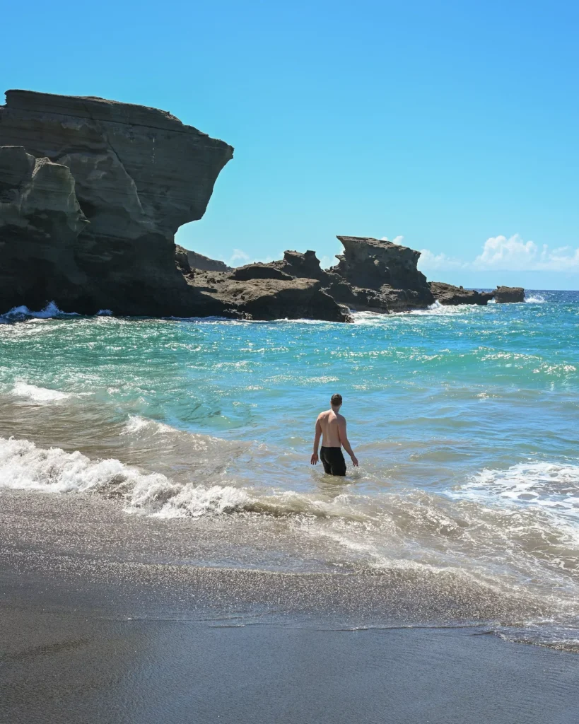Guy in the waters of green sand beach
