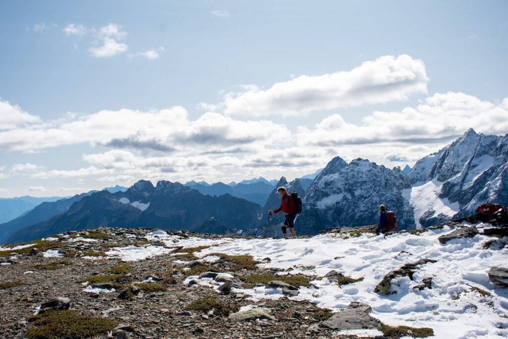 hikers going up Sahale Arm with snow on the ground and poles in their hands