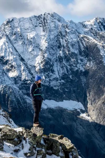 Woman standing and smiling at the top of Sahale Arm on Cascade Pass trail with snowy mountain behind her