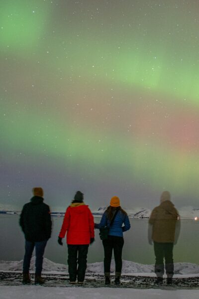 four people standing under the Northern Lights