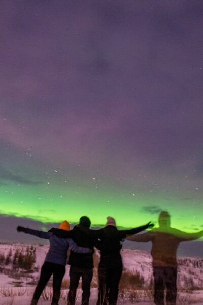 four people looking at northern lights
