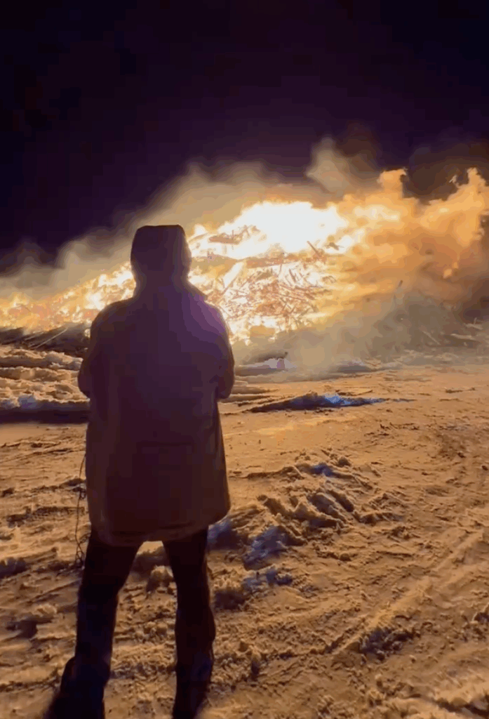 Person standing in front of large bonfire