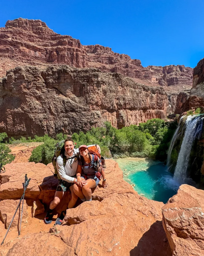 two people sitting on top of havasu falls