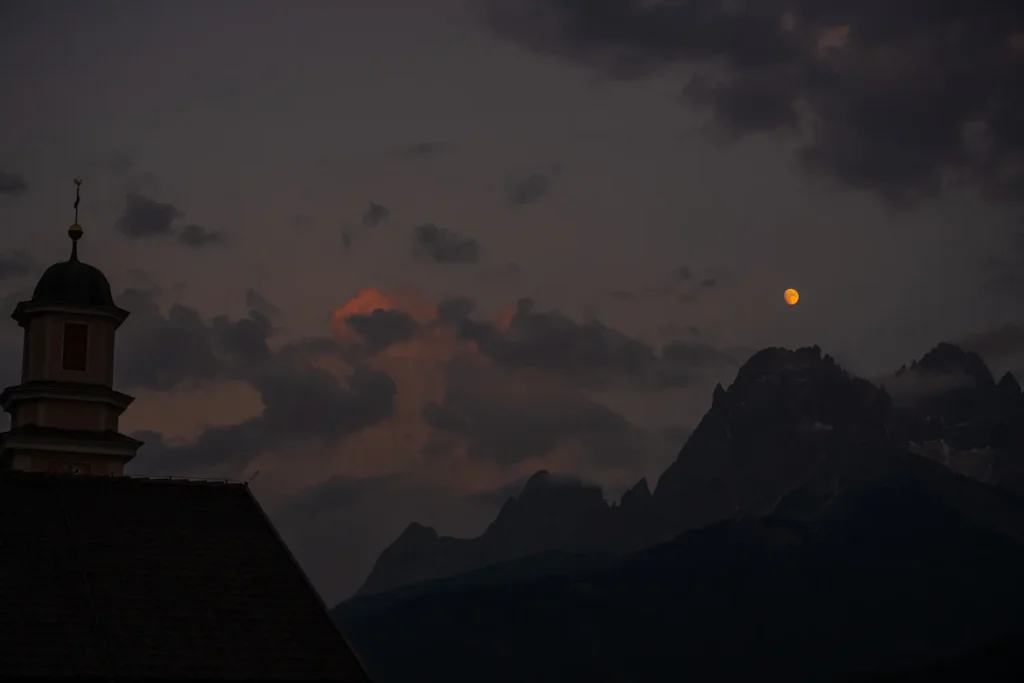 moon hanging in the air above the mountains