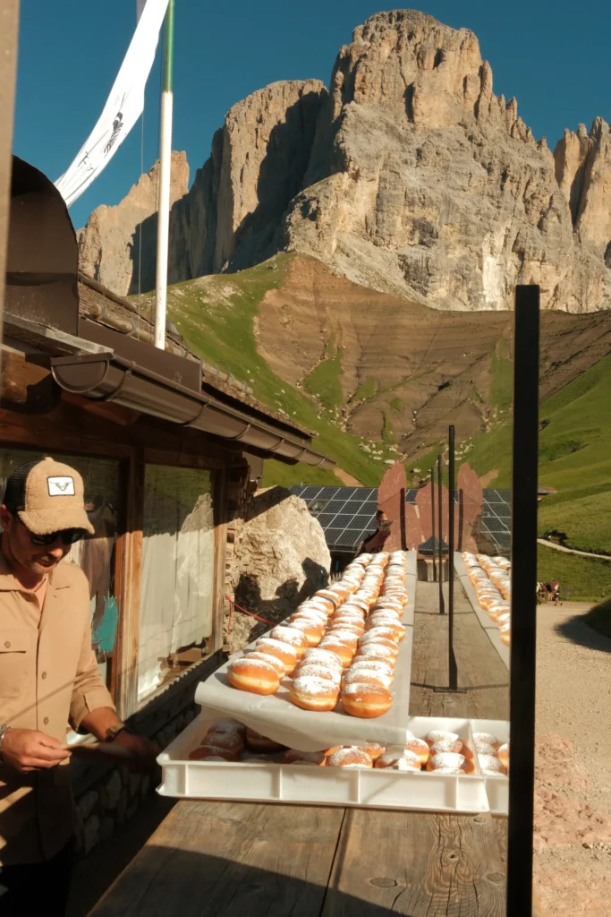 guy standing in front of krapfen donuts at rifugio freidrich august in the dolomites
