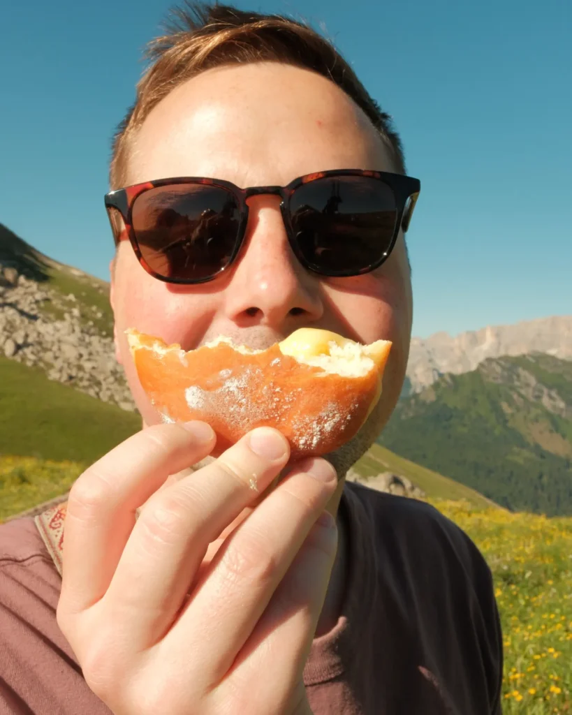 Guy smiling with half a donut in front of his face imitating a smile