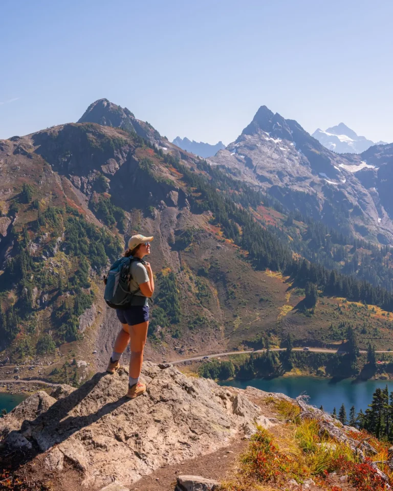 girl standing on a ledge of Winchester Mountain Trail with fall colors and Mt Baker mountain